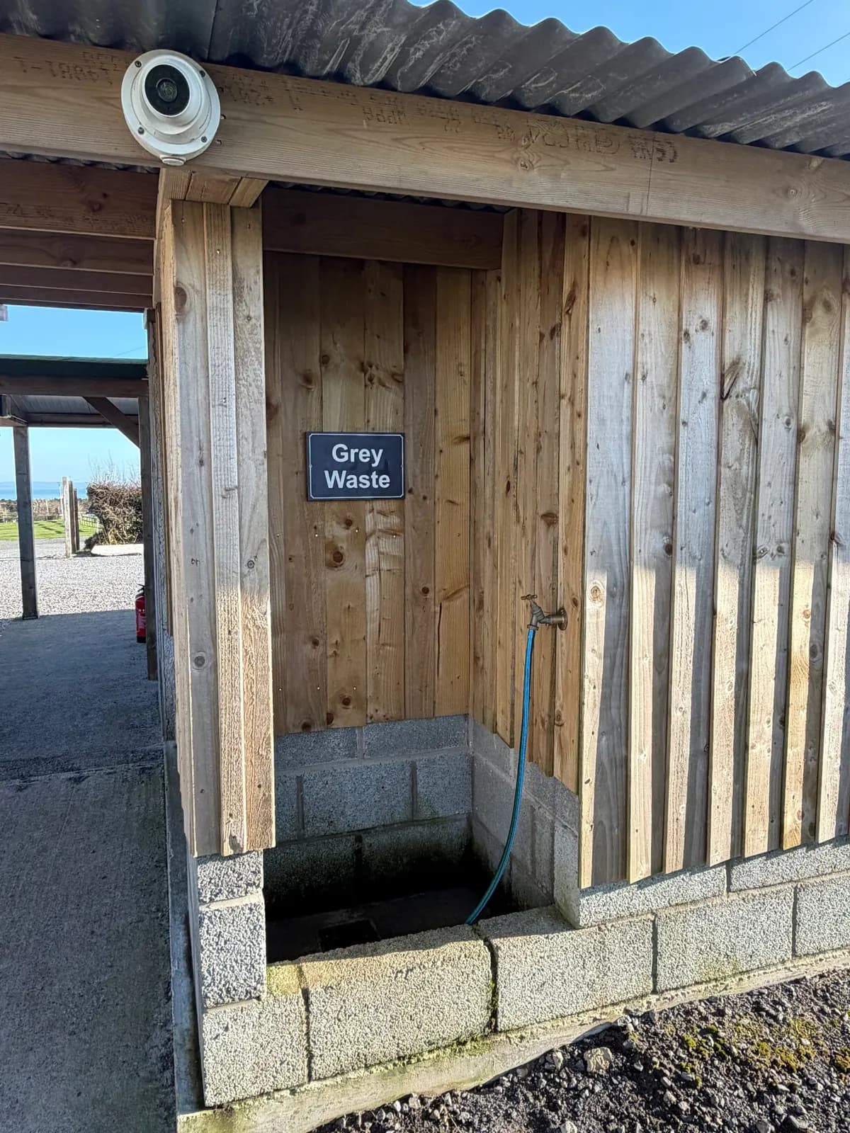 The grey waste point: a low drain with a hose, under a wooden shelter with a sign saying Grey Waste.