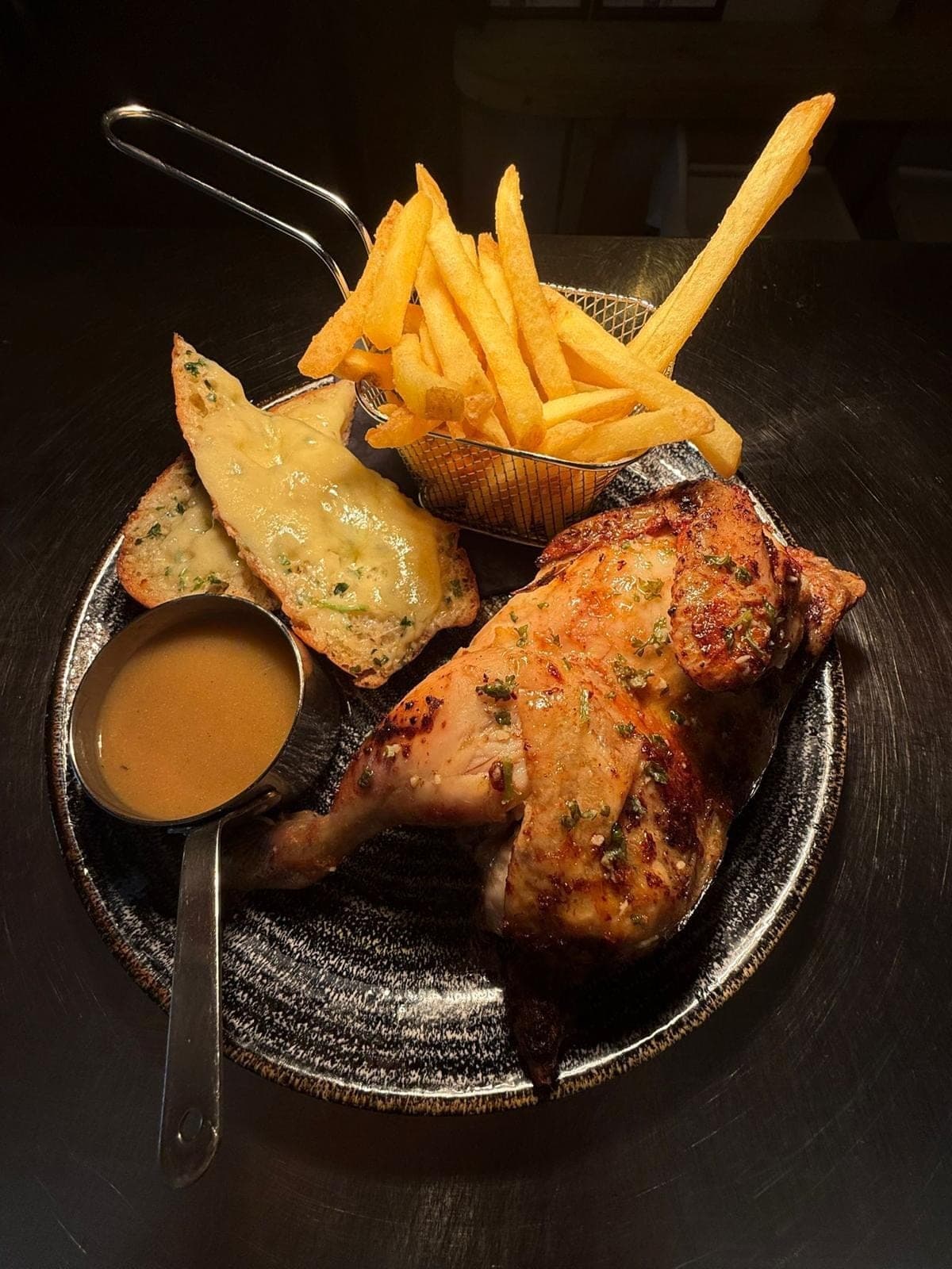 Rotisserie chicken and chips at Jan'z: half a chicken with a basket of chips, cheesy garlic bread and a pot of sauce.