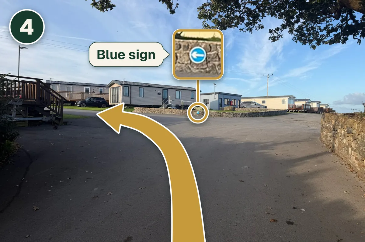 The top of the lane, with a gold arrow turning left and the little blue sign on the low wall shown larger.
